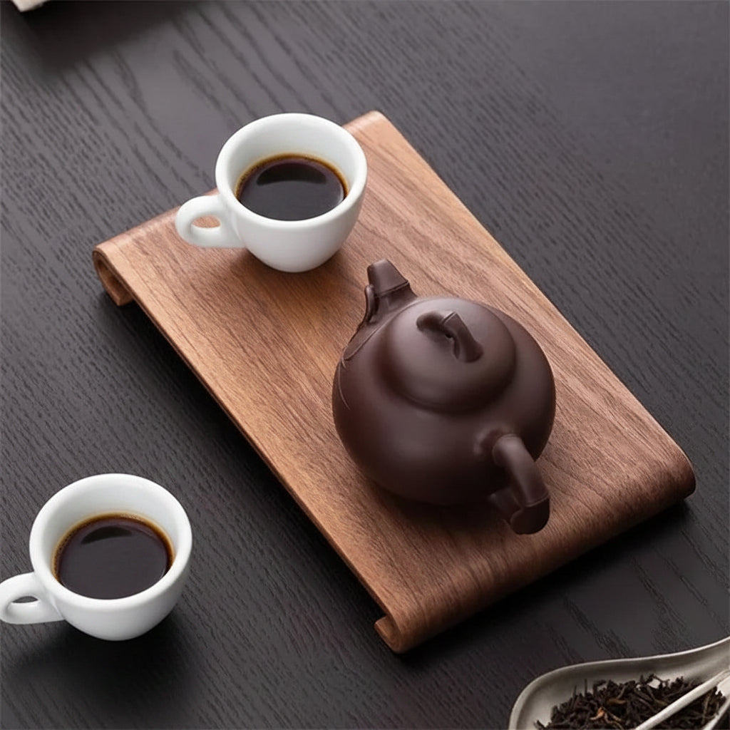 Tea set with a dark teapot and two glasses of tea on a wooden tray.