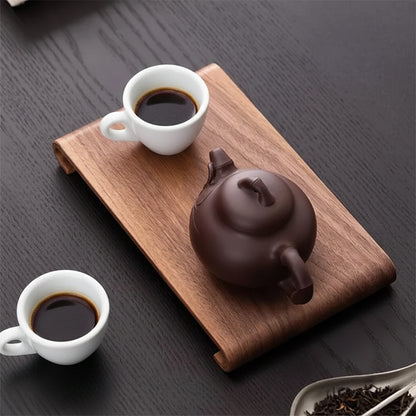 Tea set with a dark teapot and two glasses of tea on a wooden tray.