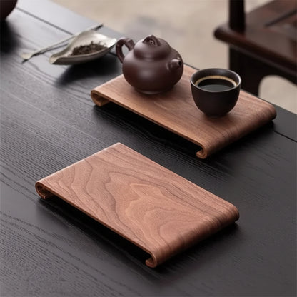 Tea set with teapot, glass of tea, and wooden tray on a dark surface