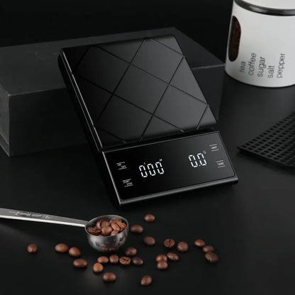 Black digital kitchen scale with coffee beans and a spoon on a dark surface