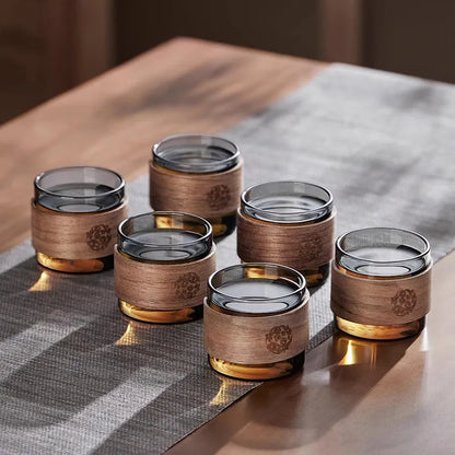 Set of glass cups with wooden accents on a reflective surface