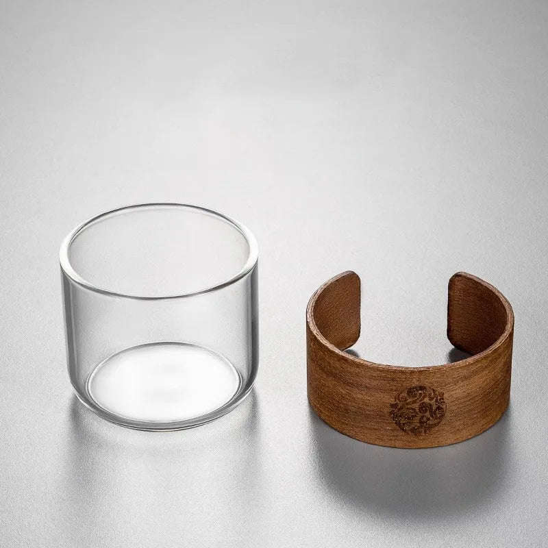 Clear glass cup and wooden bracelet on a light gray background