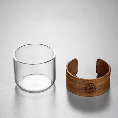 Clear glass cup and wooden bracelet on a light gray background