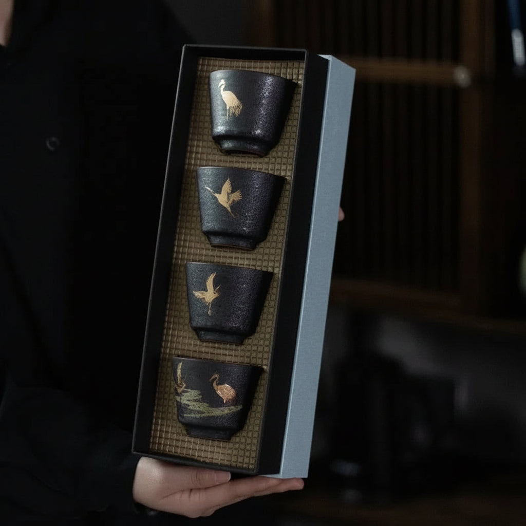 Set of four black ceramic cups with artistic designs held in a box, brand 'Yi Shuo' visible.