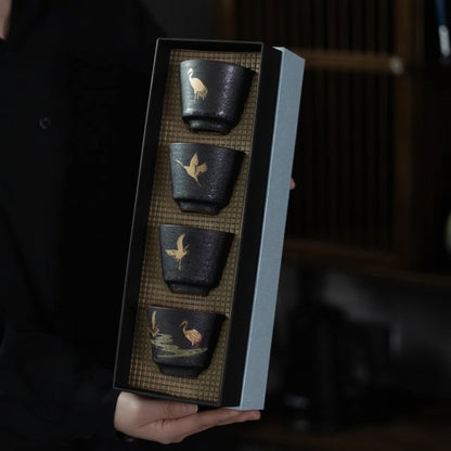 Set of four black ceramic cups with artistic designs held in a box, brand 'Yi Shuo' visible.