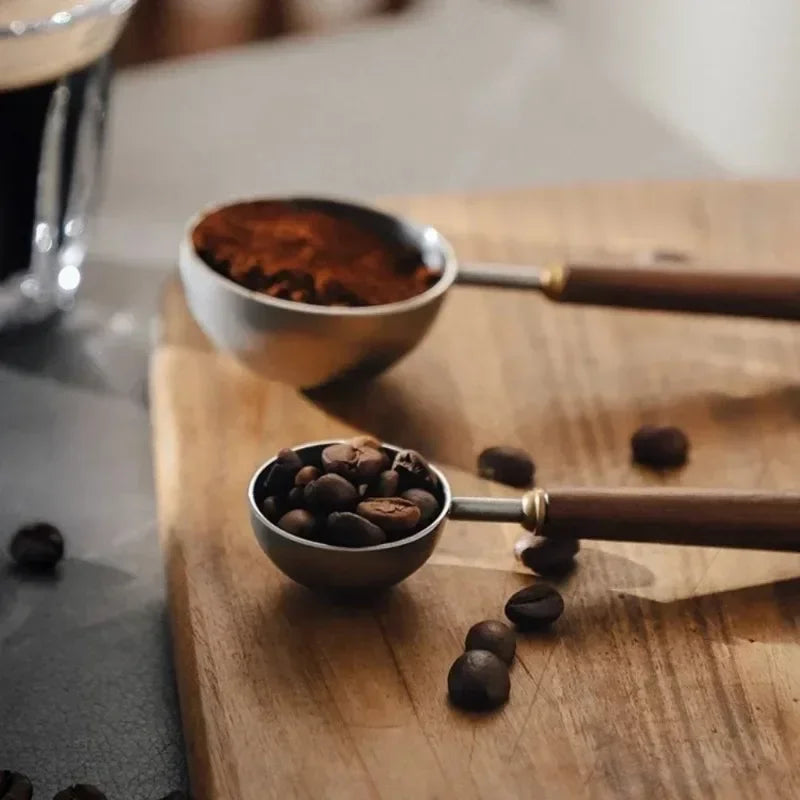 Scoops of coffee beans and ground coffee on a wooden surface