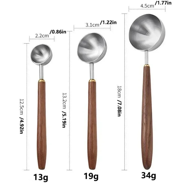 Three metal measuring spoons with wooden handles shown on a white background.