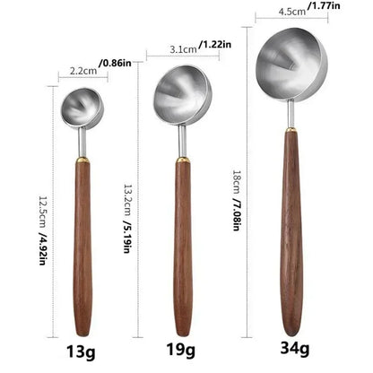 Three metal measuring spoons with wooden handles shown on a white background.