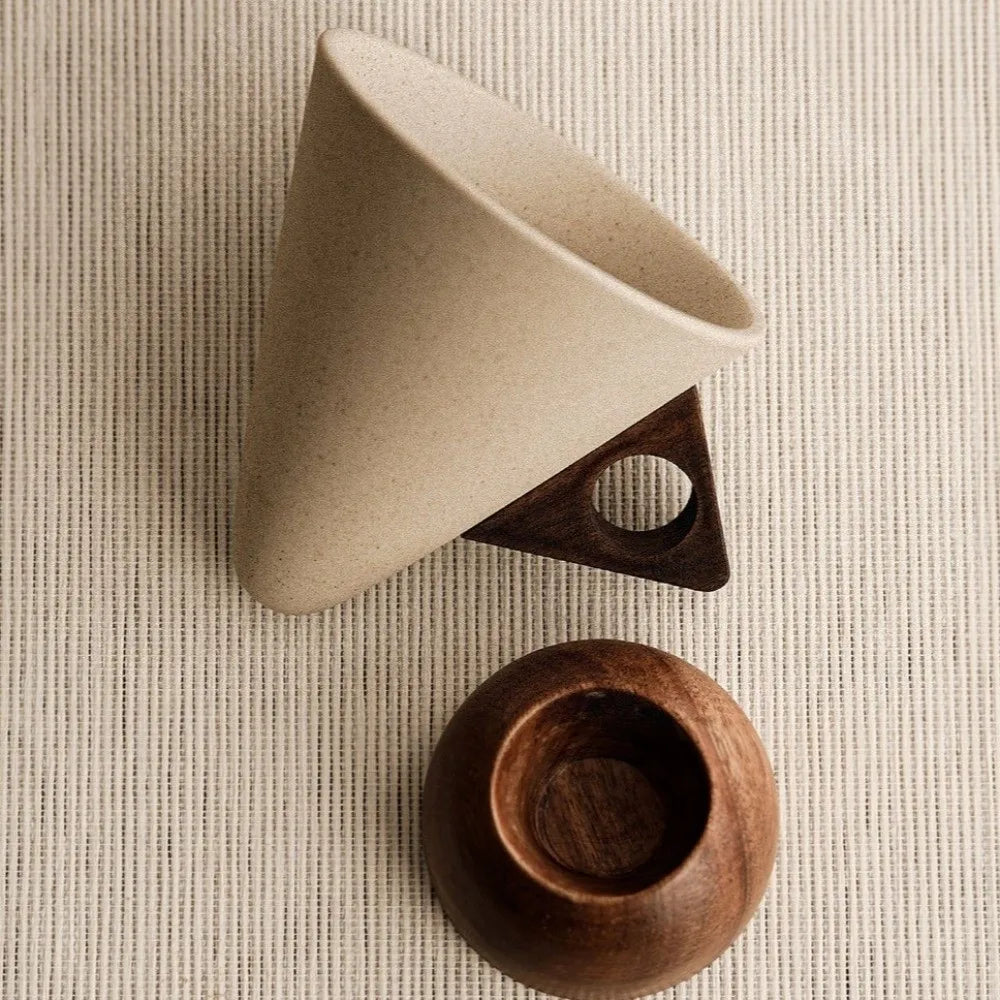 Beige ceramic cup with wooden base on a textured beige surface