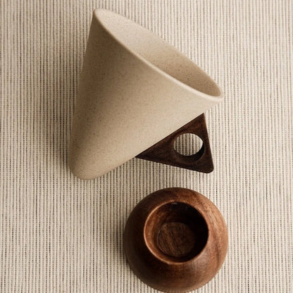 Beige ceramic cup with wooden base on a textured beige surface
