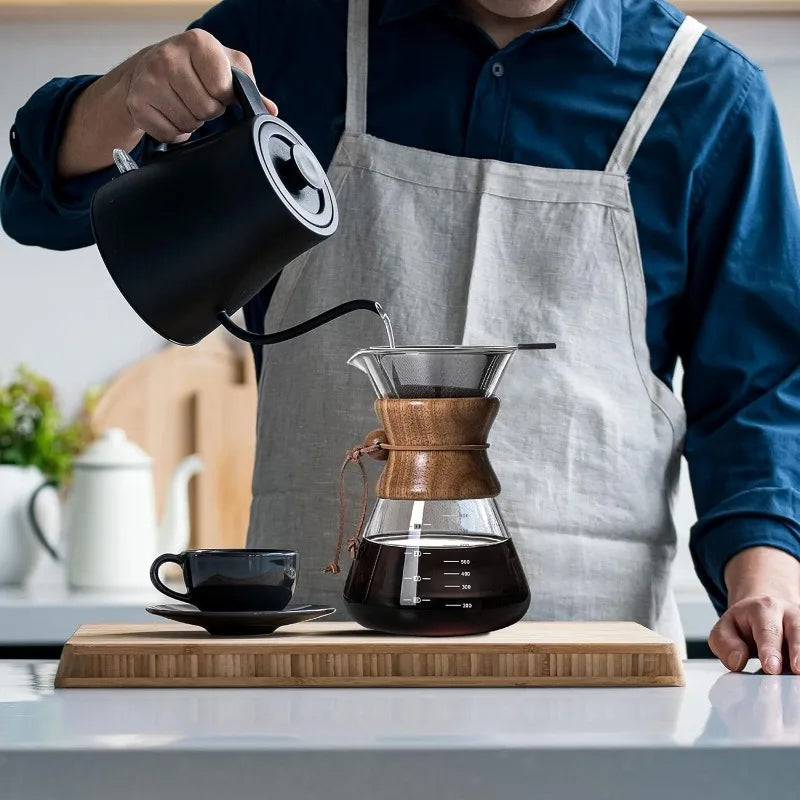 Person in a kitchen pouring coffee from a kettle into a wooden coffee dripper.