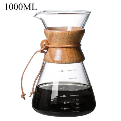 Clear glass coffee maker with wooden lid and black liquid inside, on a white background.