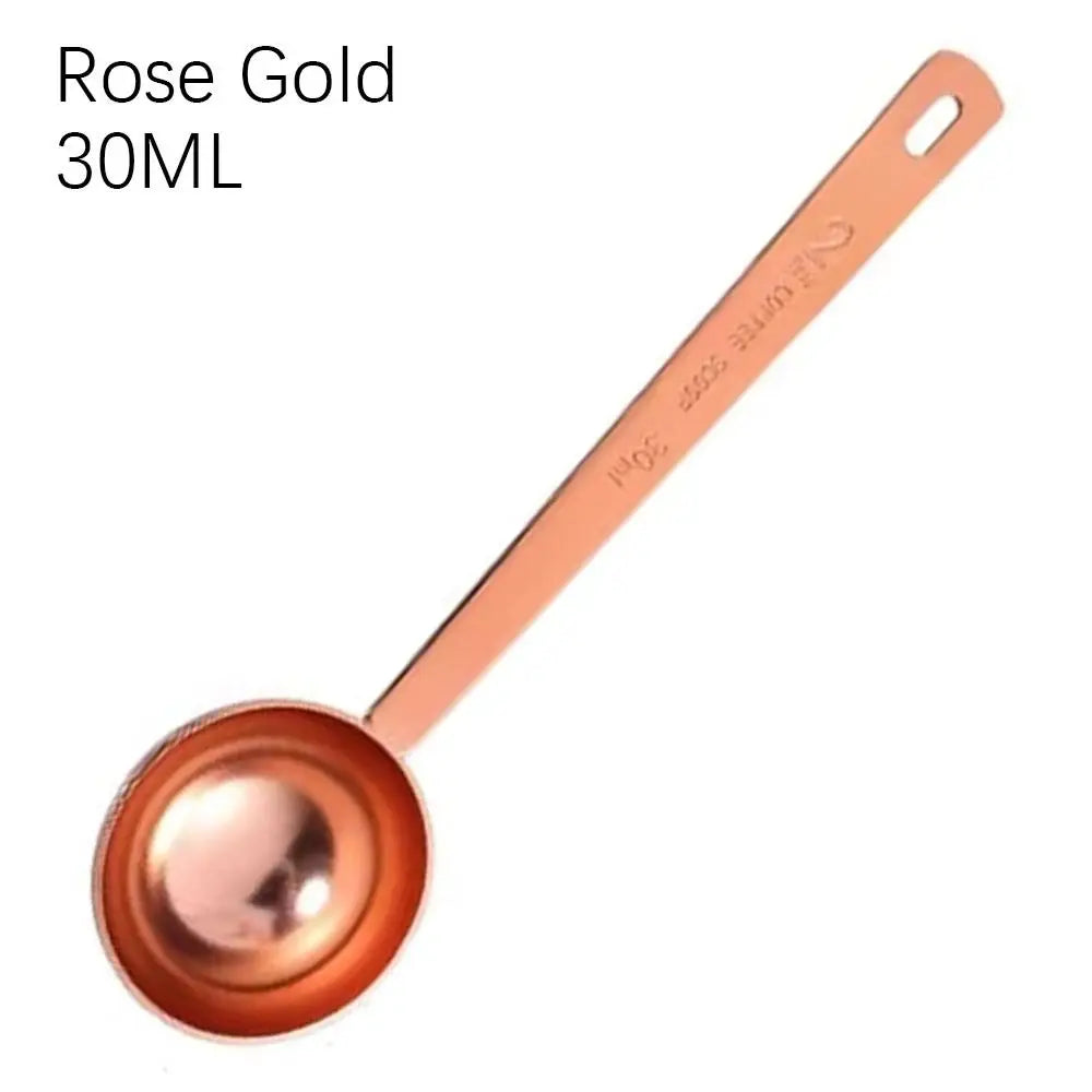 Rose gold measuring spoon with 'NOS' branding on a white background