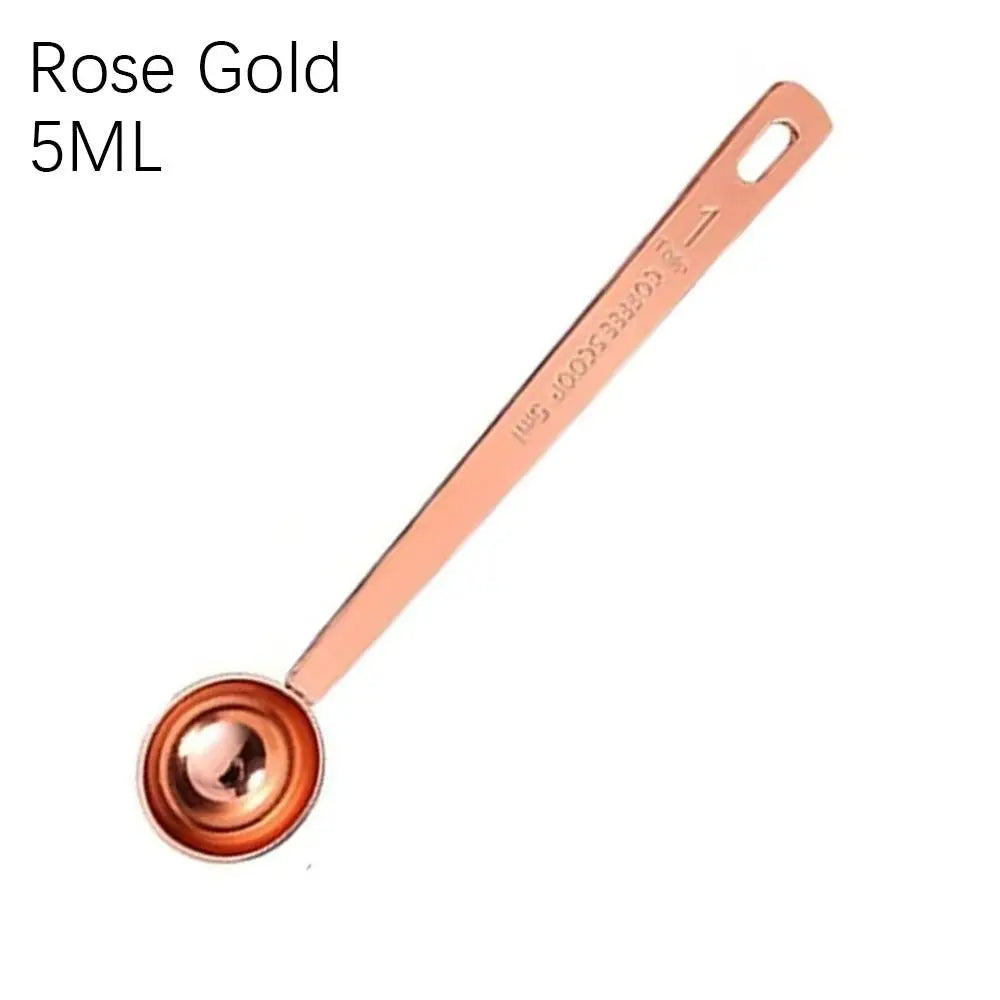Rose gold measuring spoon with '5ML' marking on a white background