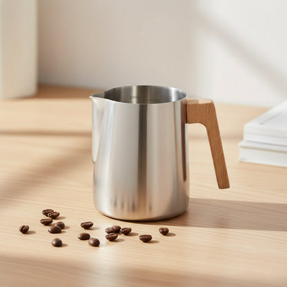 A stainless steel milk pitcher with a light brown wooden handle