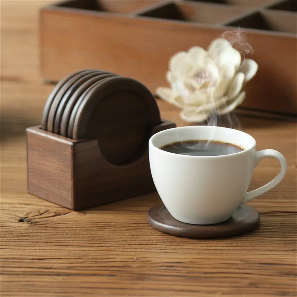 Clear glass mug with tea on a wooden coaster, next to a wooden coaster holder and coffee cup