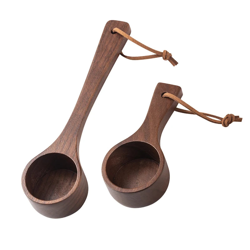 Two wooden measuring spoons with leather straps on a white background
